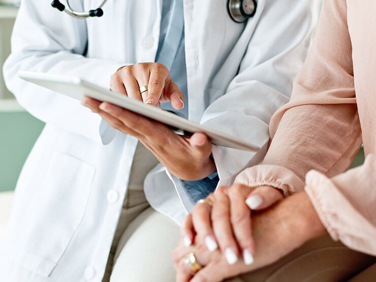 Hands and shoulders view of a health care practitioner discussing a chart with a patient