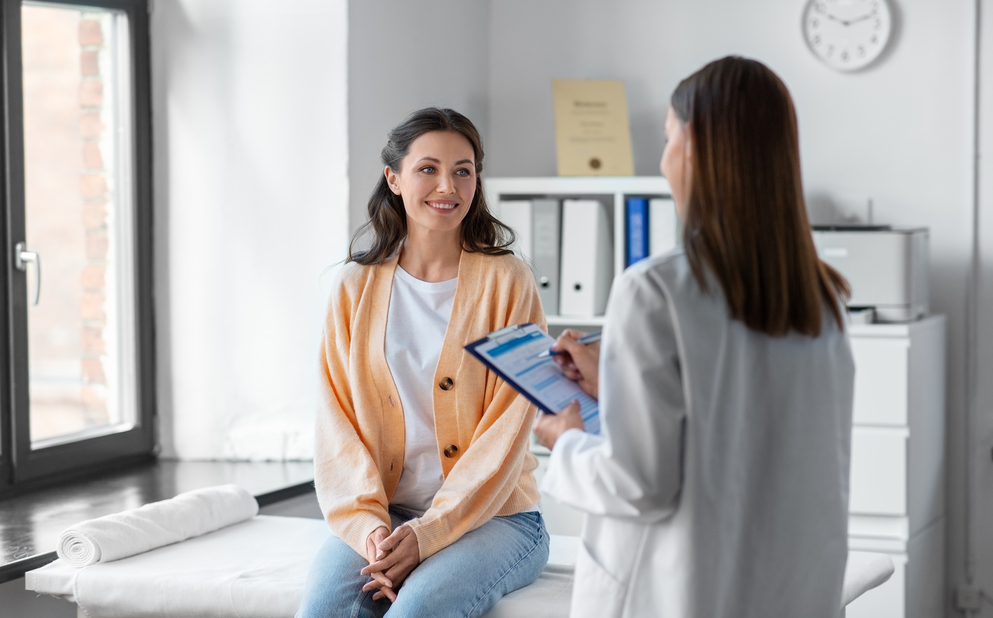 Female doctor visiting female patient and filling out EHR