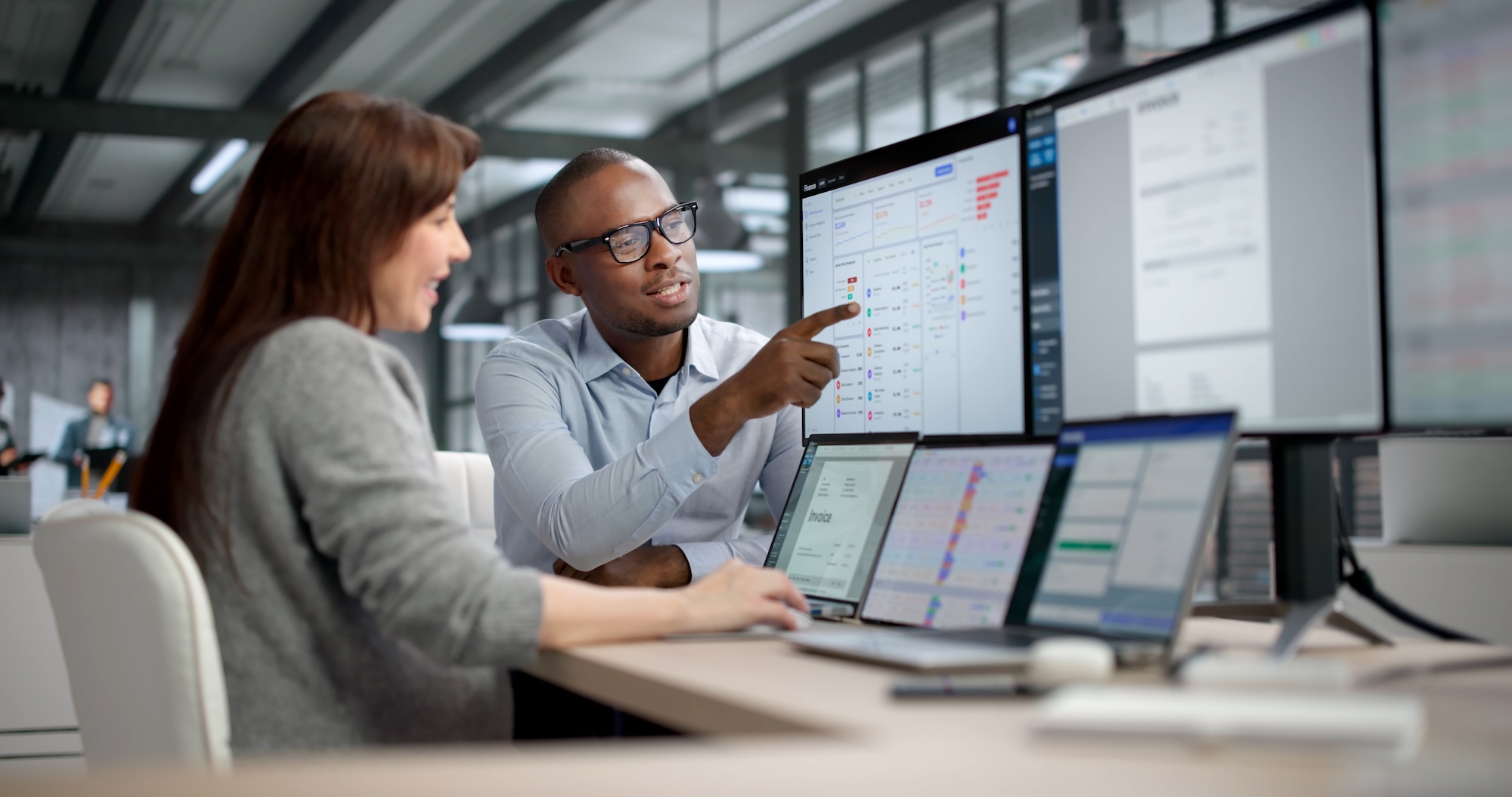 Two Professionals Analyzing Reports And Tracking Data On Computer Screens