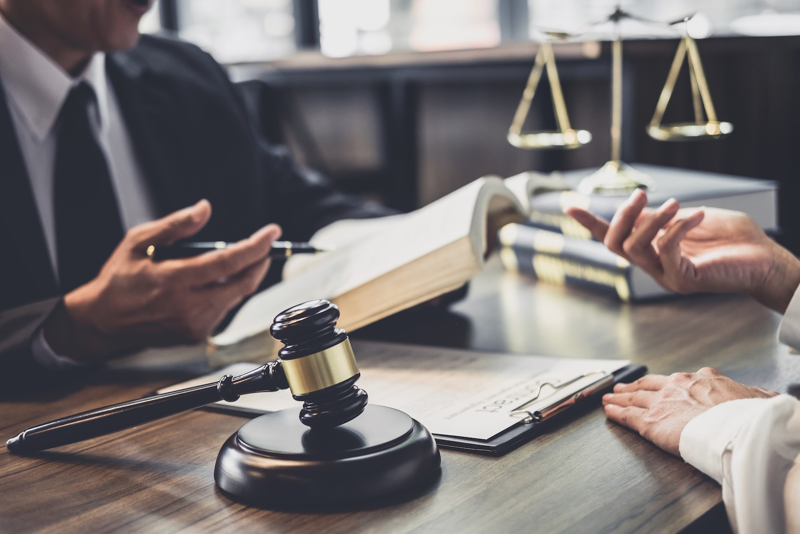 Justice scales, gavel, and hands of people discussing justice