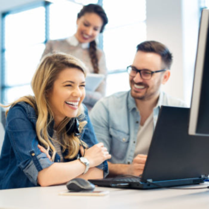 woman laughing at computer with coworkers